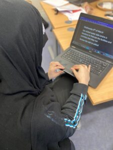 Mini is sat at a desk typing on a computer
