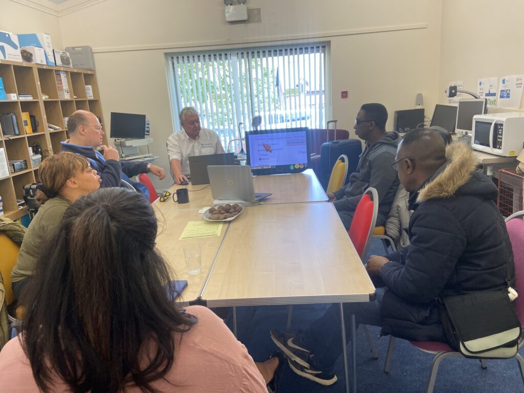 a group of people sat round a table having a demo of some accessible software