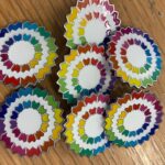A pile of pins. The pins is the brightly coloured wheel from Berkshire Vision's logo as a enamel pin .