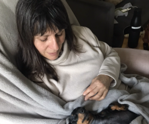 A photo of sarah with a daschund sat on her lap